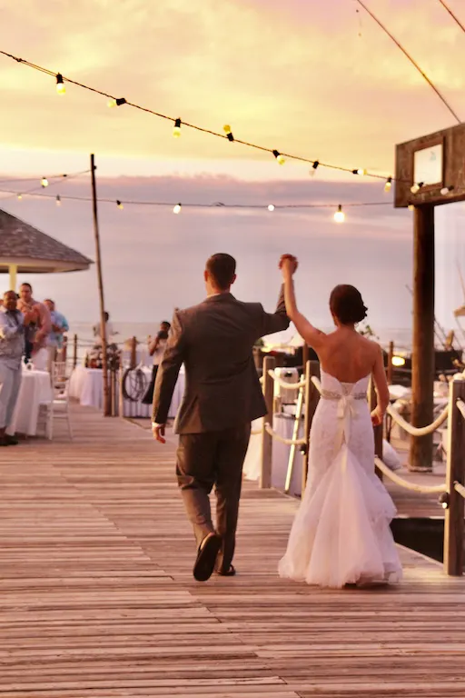 Bride and Groom holding hands in the air by the sea