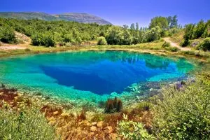 Cetina river Spring with landscape view, Cetina River Spring, Cetina River Spring: Where Is It Located?  Cetina (pronounced [tstina]) is a river in southern Croatia. It is one of the famous landmarks of continental Croatia. It is 101 kilometers (63 miles) long and has a basin area of 1,463 kilometers (565 sq mi). Cetina flows to the Adriatic Sea from its headwaters 385 meters (1,263 feet) above sea level. It is the most water-rich river in Dalmatia.  The Spring of Cetina is at an altitude of 1,065 meters (3,493 feet) on the slopes of Mali Gradac mountain. It is close to Smiljevica village, on the road from Sinj to Omiš. Beech trees and bushes with wild strawberries surround the Spring.   The water comes from a small cave between rocks. Also, it looks like it's still coming from underground water springs. The smell of sulfur comes from this water. But it can't be seen because the smell disappears as soon as you pour it into glasses or bottles. You can spend your long weekend here in these beautiful Croatian Islands,.Croatia in Spring